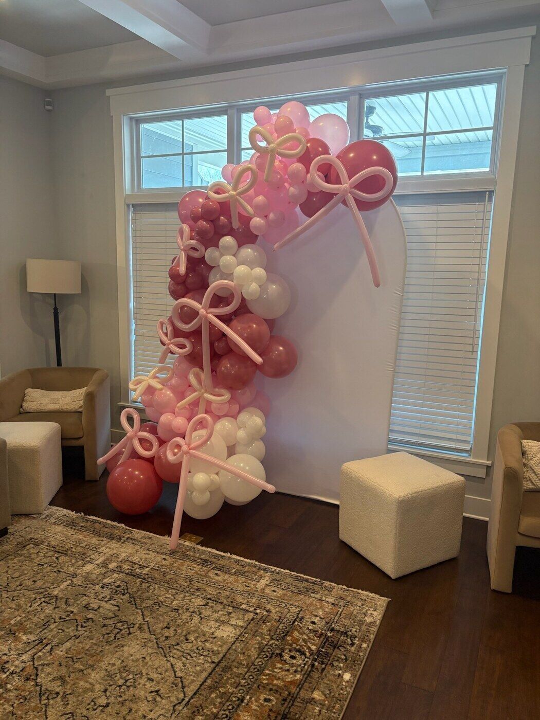 Pink and white balloon garland with bows on a blush arch backdrop