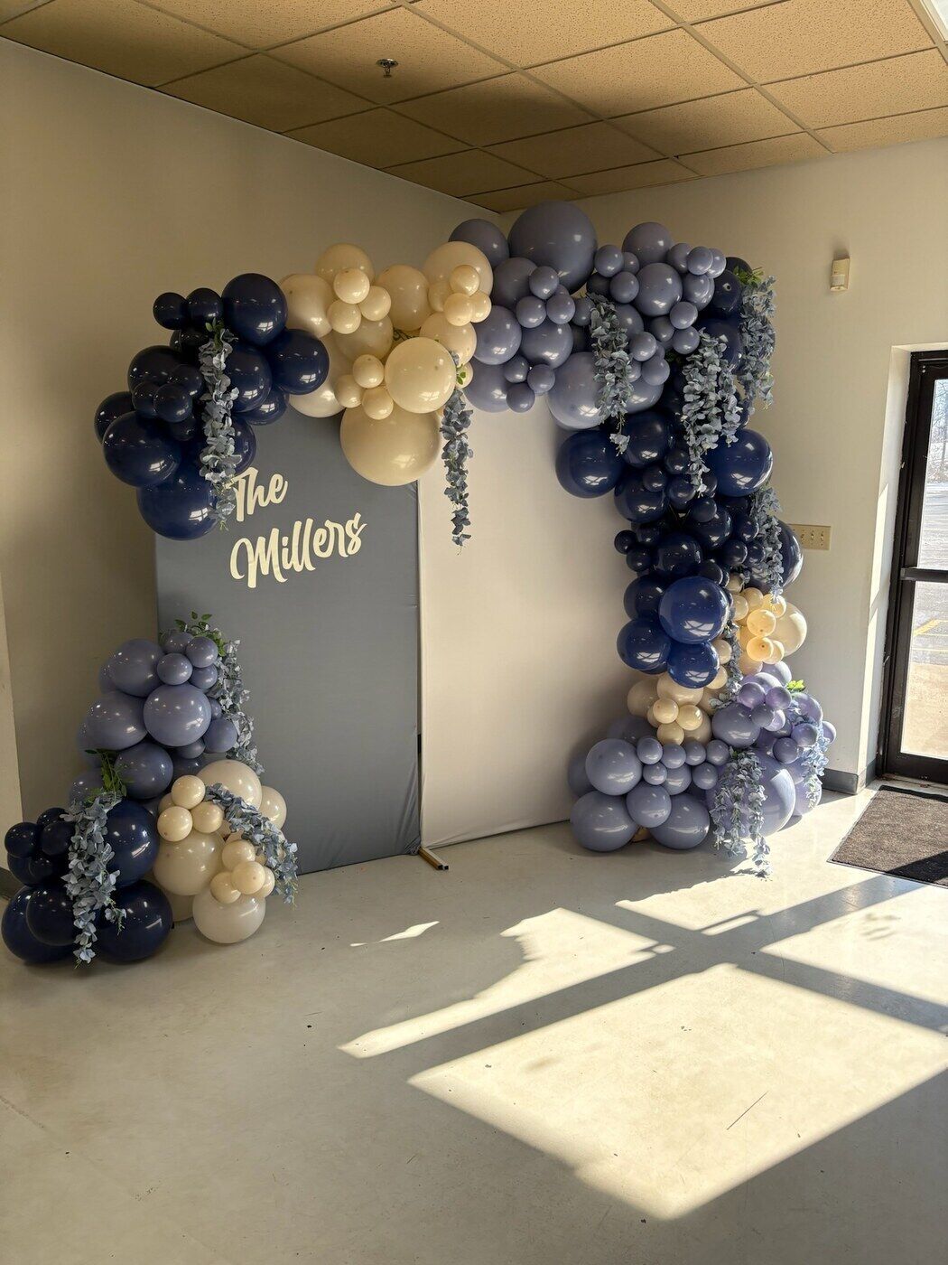 Navy and cream balloon arch framing a personalized family backdrop