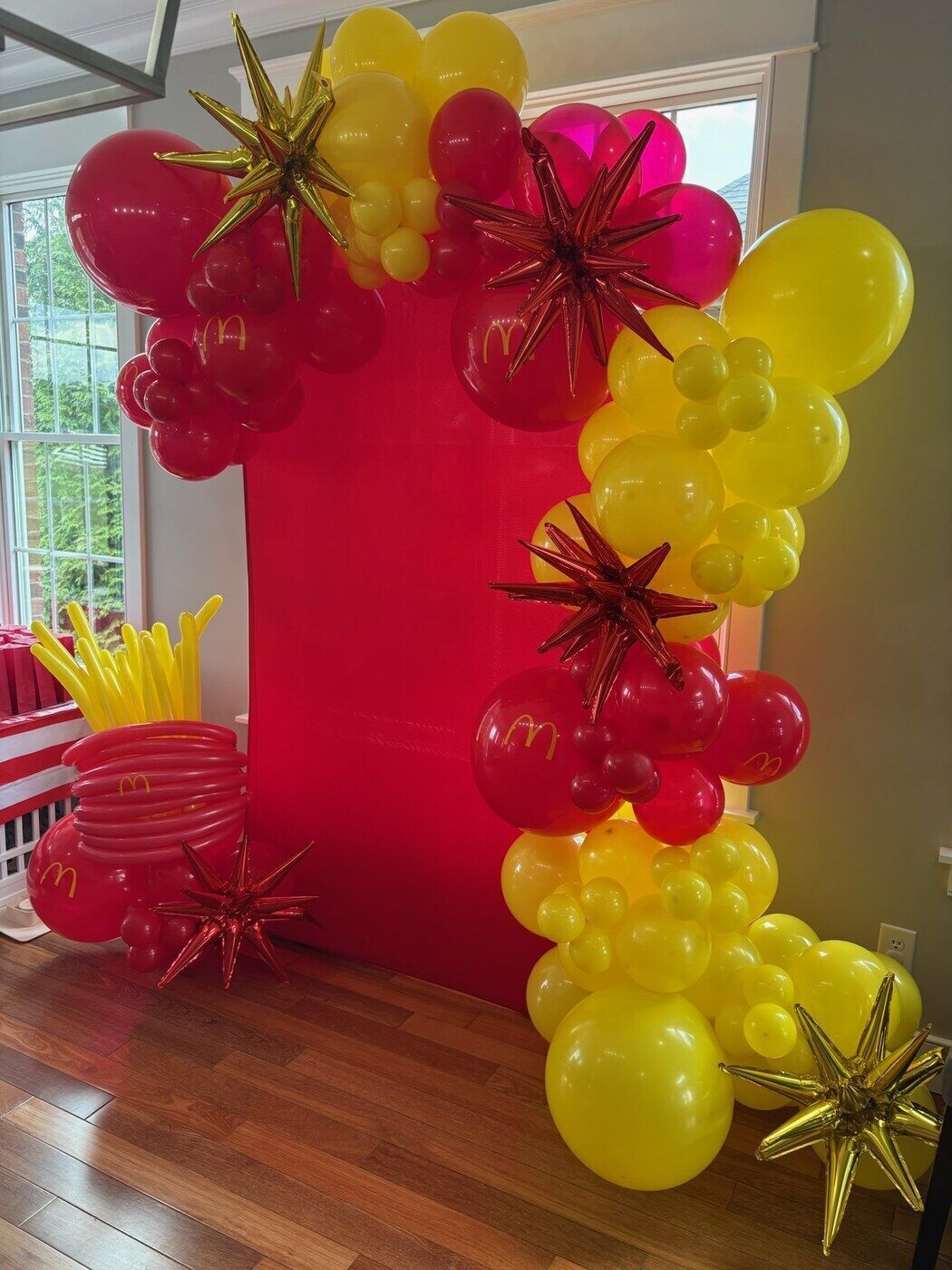 Red and yellow balloon arch with starburst accents