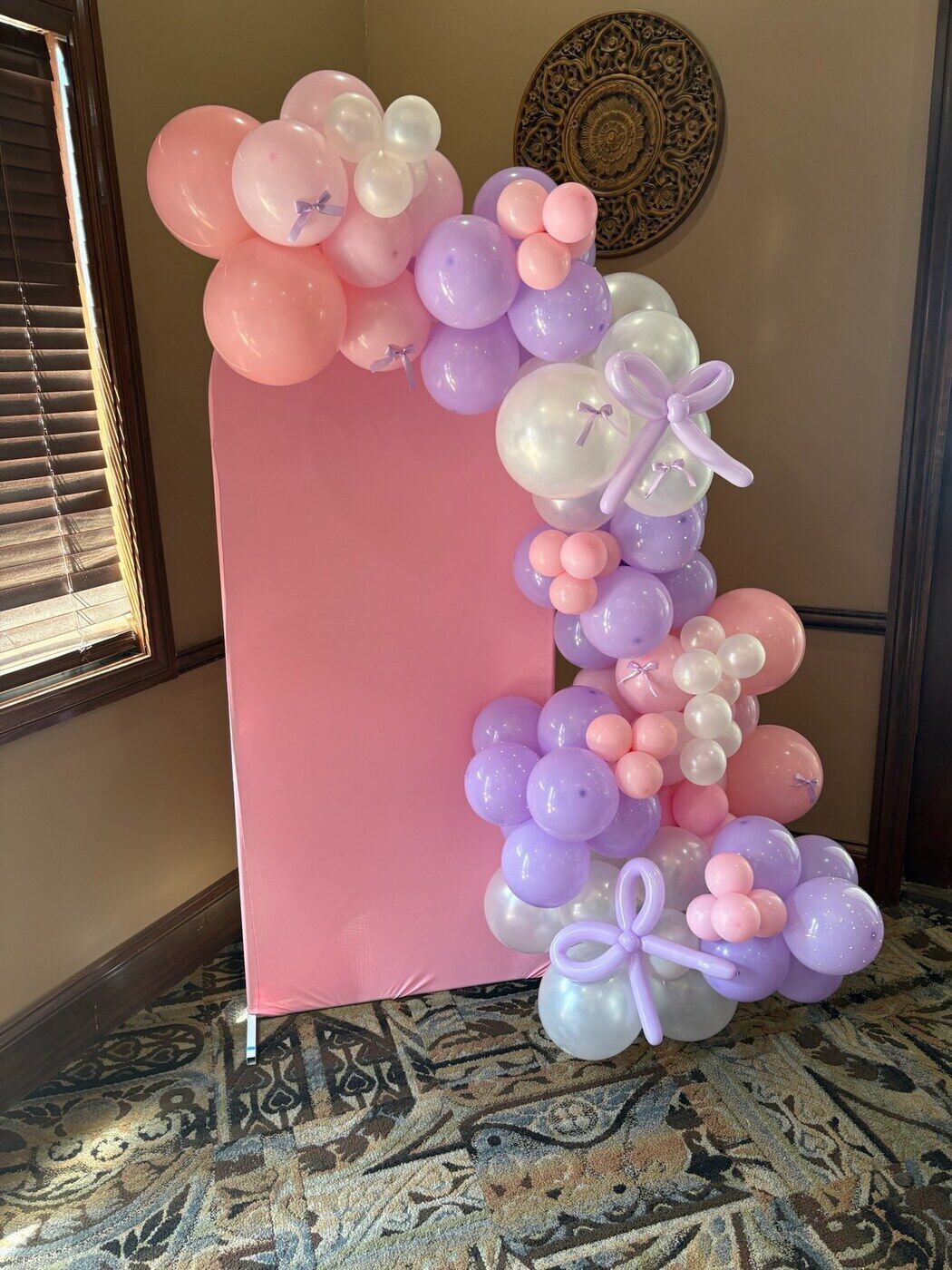 Pink and lilac balloon garland on a blush arch backdrop