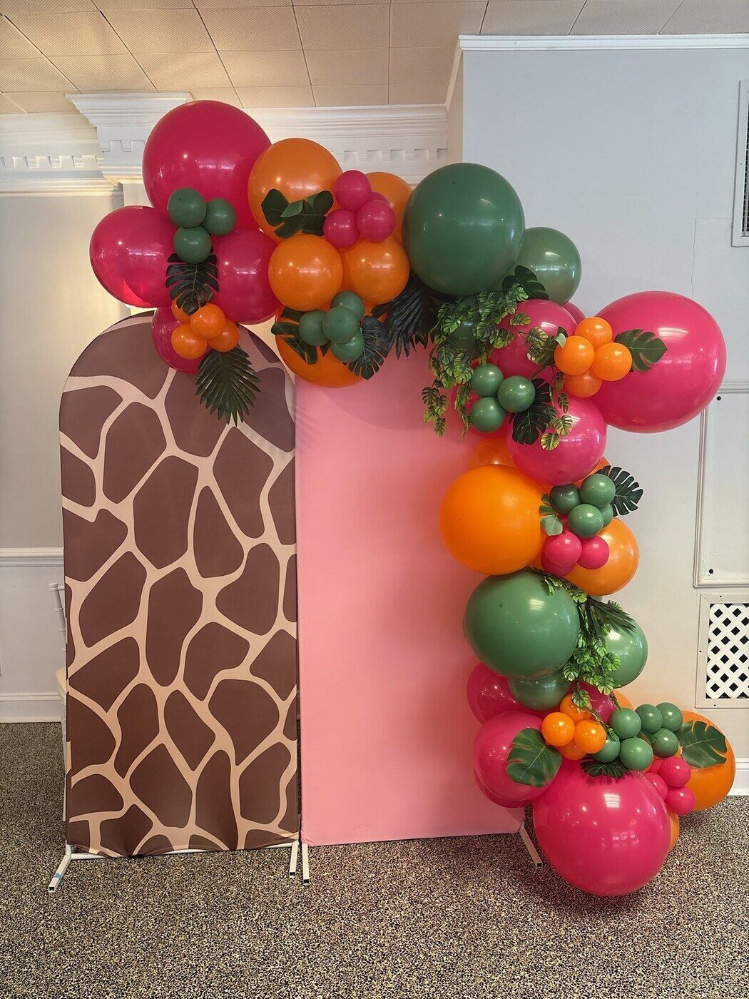 Safari themed balloon arch with a giraffe print backdrop