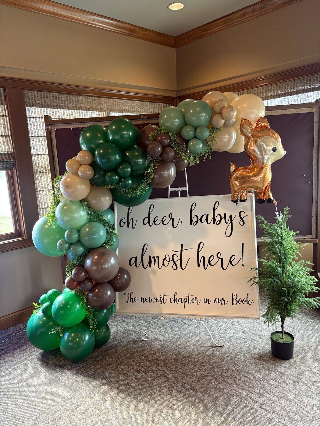 Woodland baby shower balloon arch with a hand lettered sign