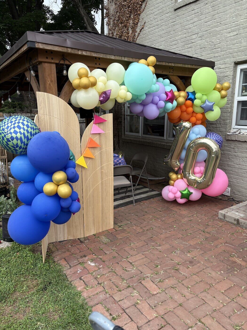 Outdoor 40th birthday balloon arch with a gold foil number over a patio
