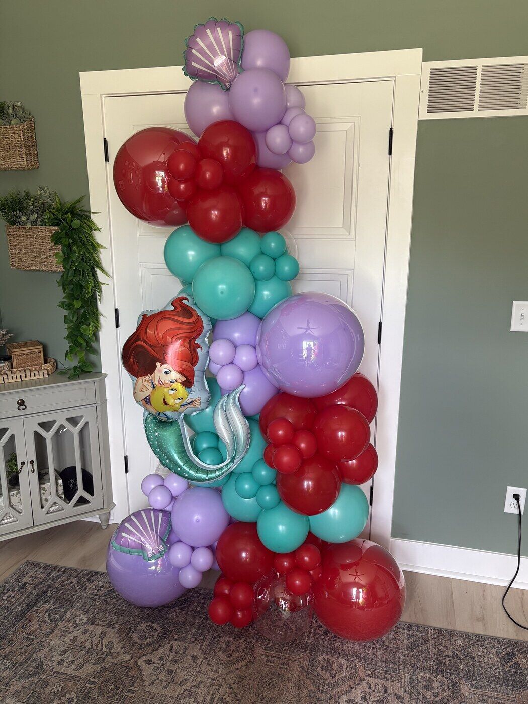 Little Mermaid balloon column in red, teal and lavender beside a doorway