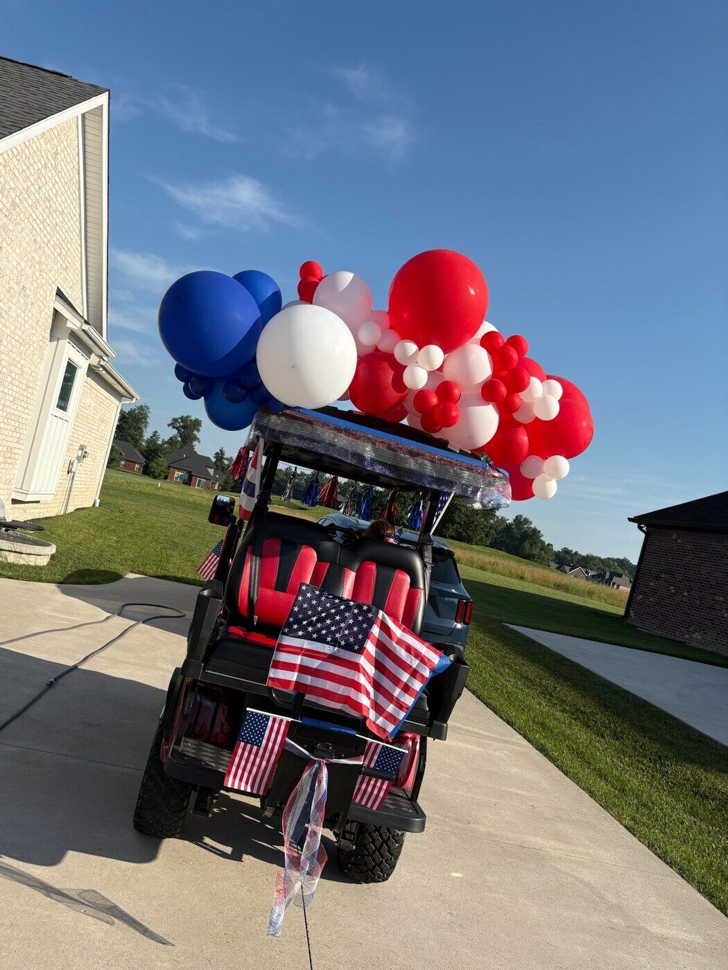 Patriotic red, white and blue balloons decorating a golf cart outdoors