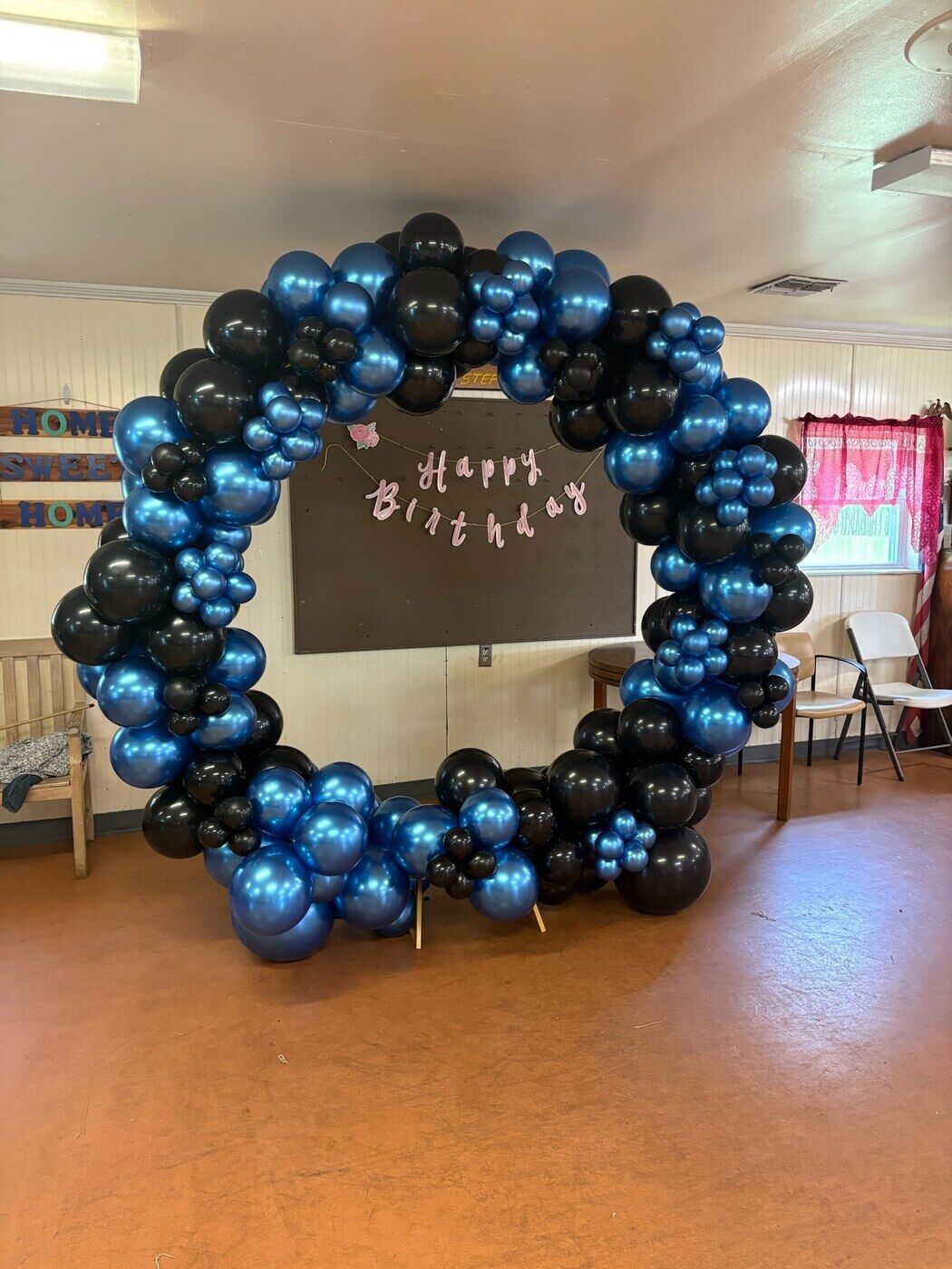 Navy and black balloon circle arch around a happy birthday chalkboard