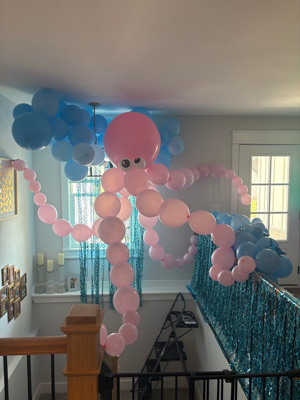Pink octopus balloon sculpture over a stair railing
