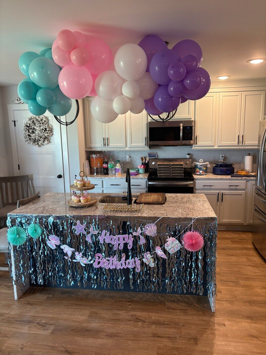 Pink and teal birthday balloon garland over a dessert table