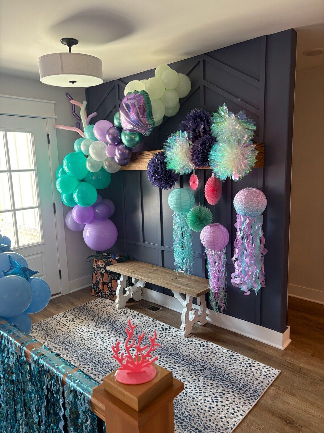 Teal and purple jellyfish balloon display above an entry bench