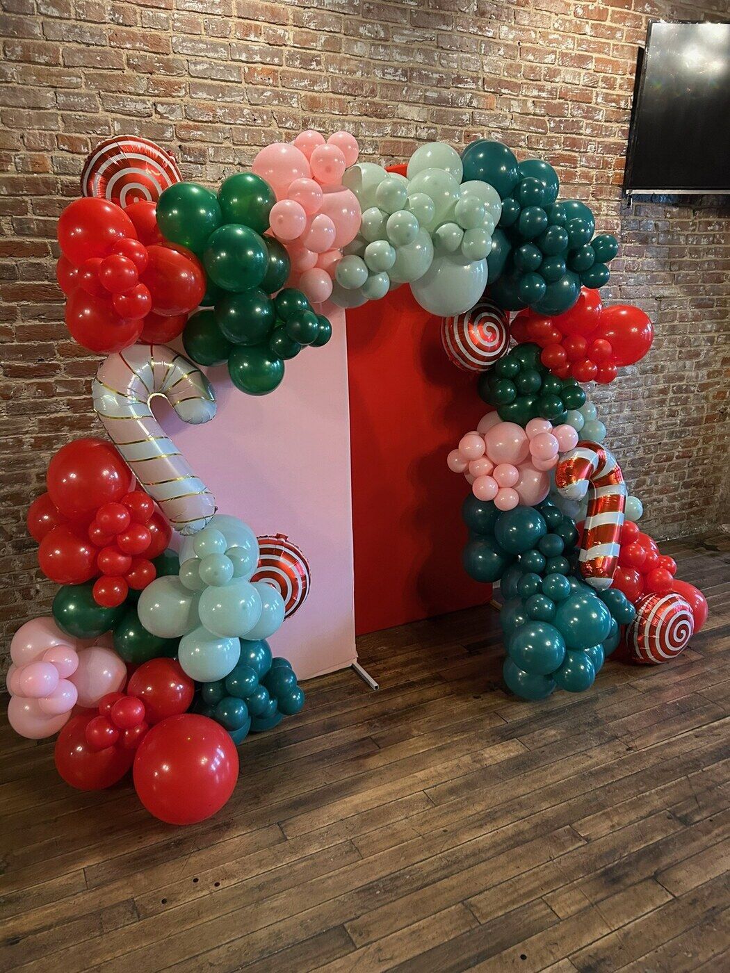 Christmas balloon arch in red and green with candy cane accents