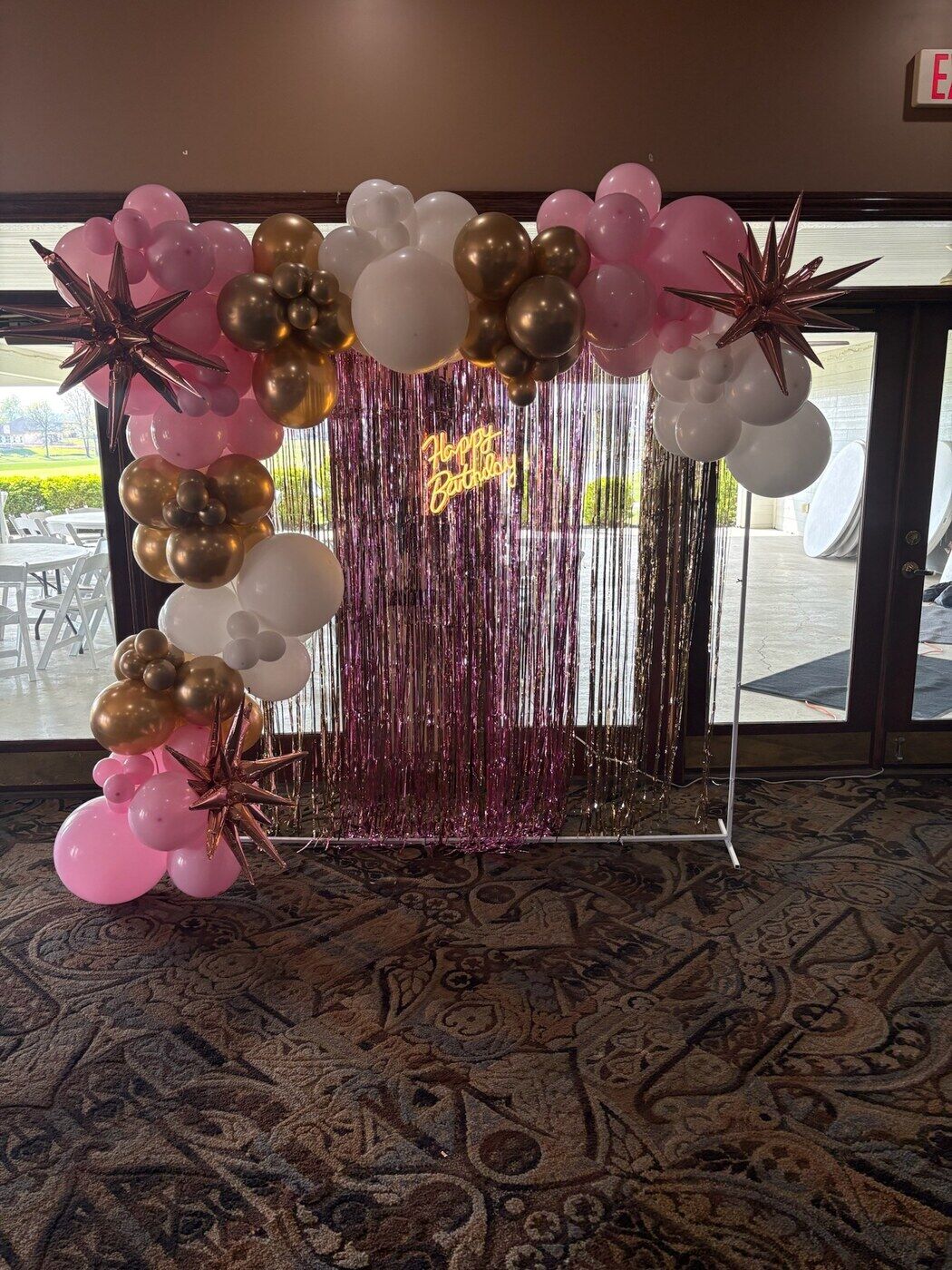Rose gold and pink balloon garland over a fringe curtain